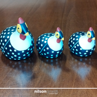 Foto de três galinhas de angola de argila, pintadas, de diferentes tamanhos.