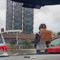 Foto de pessoa em situação de rua com cartaz escrito fome.